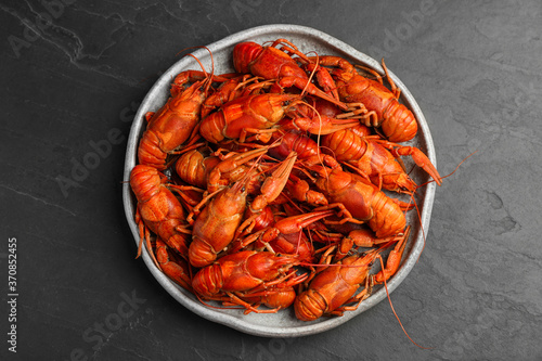 Delicious boiled crayfishes on black table, top view