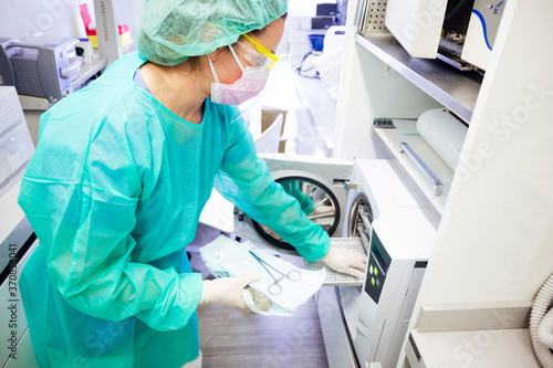 Female dentist sterilizing medical instruments in clinic photo