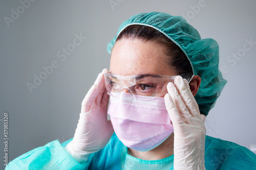 Close-up of nurse wearing protective eyewear looking away in clinic