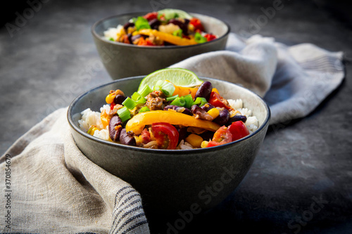 Two bowls of Mexican rice with bell peppers, tofu, kidney beans, tomatoes, corn, lime and scallion photo