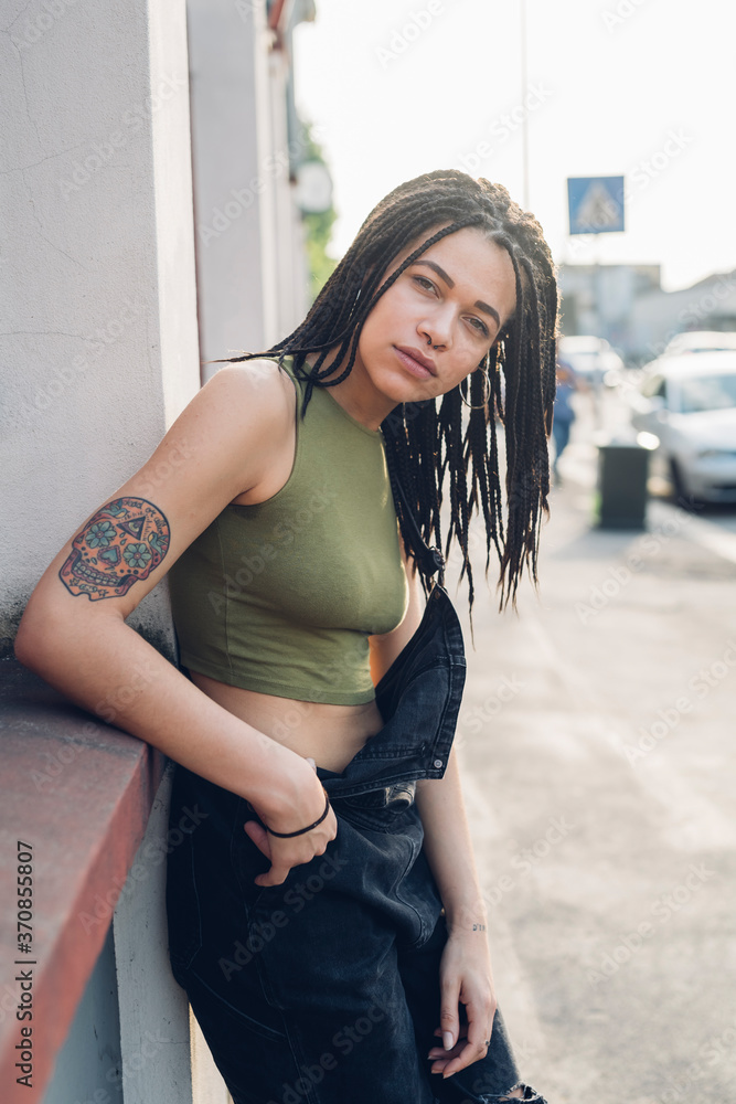 Portrait of a confident stylish young woman leaning against a wall in the city Portrait of a confident stylish young woman leaning against a wall in the city