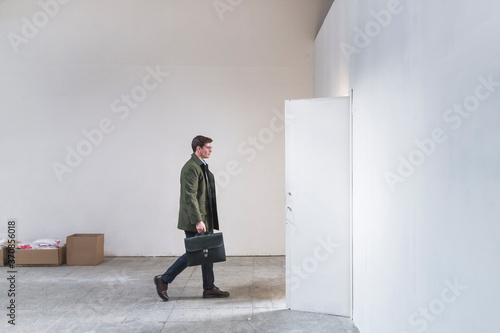 Businessman with briefcase leaving sparse room