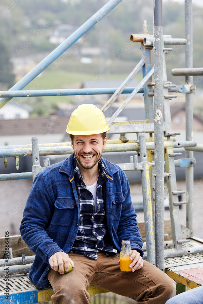 Portrait of a happy worker having a break on scaffolding on a construction site Portrait of a happy worker having a break on scaffolding on a construction site