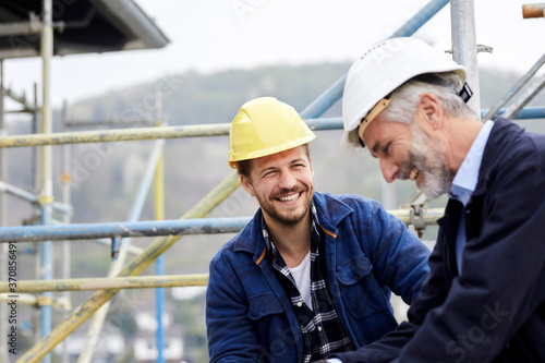 Happy architect and worker on scaffolding on a construction site photo