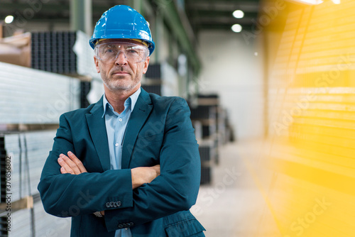 Portrait of mature businessman wearing hard hat and safety goggles in a factory photo