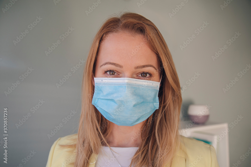 Close-up of businesswoman wearing mask against wall in office Close-up of businesswoman wearing mask against wall in office
