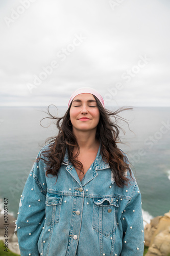 Smiling female cancer survivor with eyes closed standing against sea