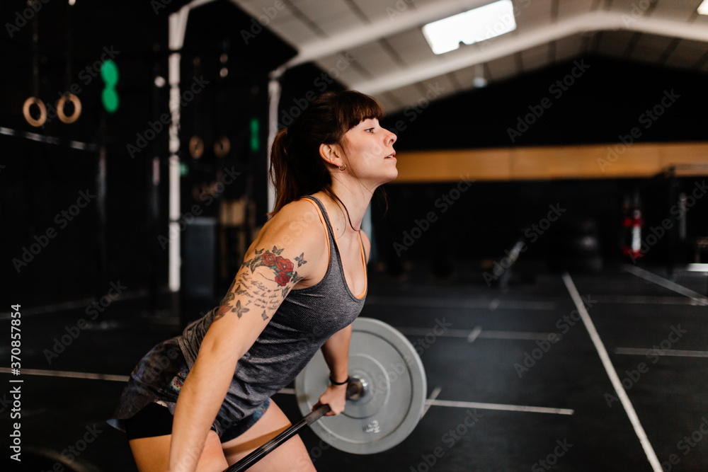Mid adult woman lifting deadlift while standing in health club