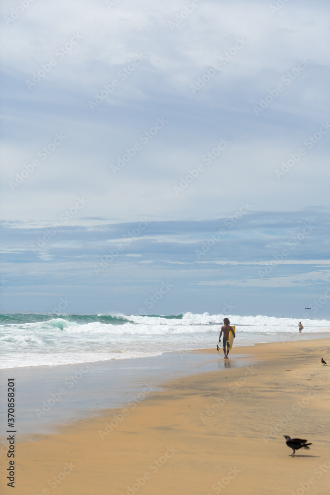 surfer on the beach, sunny day and cloudy sky, Arugam Bay, Sri Lanka