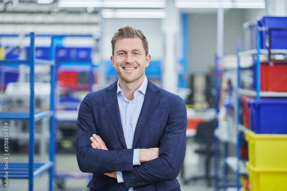 Confident male supervisor standing arms crossed in factory Confident male supervisor standing arms crossed in factory
