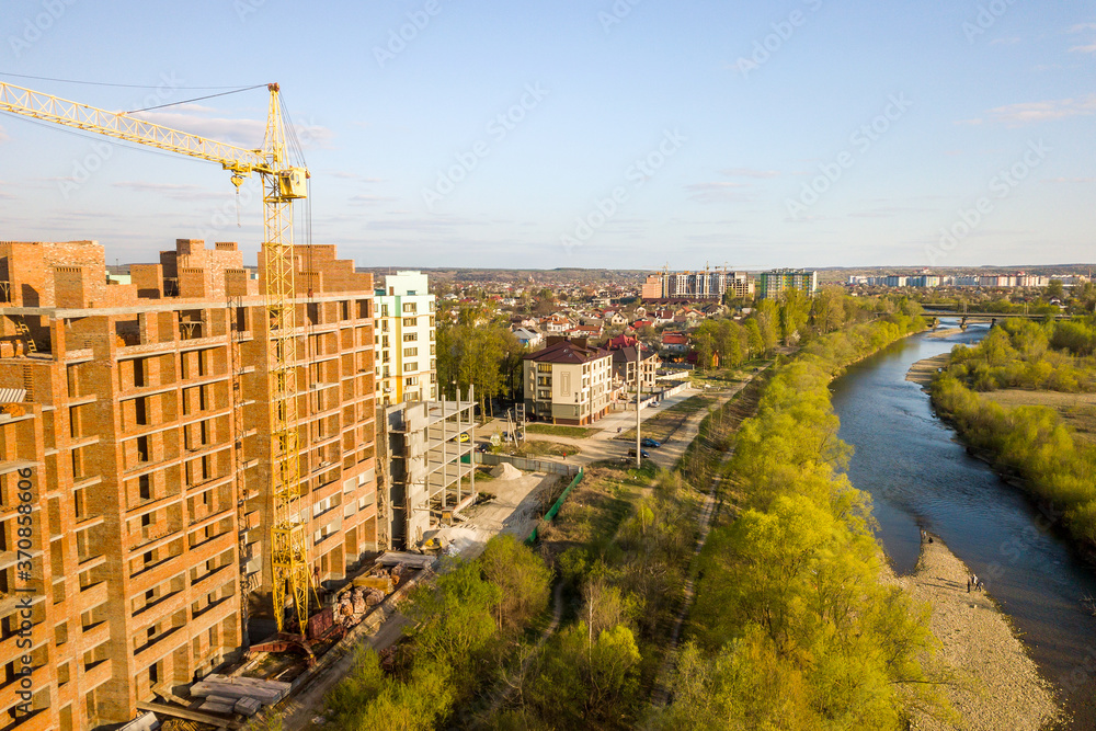 Fototapeta premium Aerial view of tall residential apartment buildings under construction and Bystrytsia river in Ivano-Frankivsk city, Ukraine.