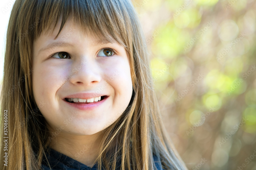 Portrait of pretty child girl with gray eyes and long fair hair smiling outdoors on blurred bright background. Cute female kid on warm summer day outside. Portrait of pretty child girl with gray eyes and long fair hair smiling outdoors on blurred bright background. Cute female kid on warm summer day outside.