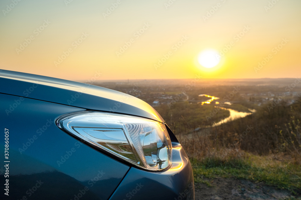 Close up detail of front headlight lamp of modern car at sunset.