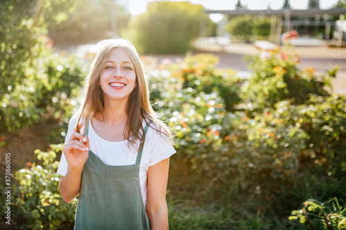 Portrait of smiling young woman in public garden at backlight