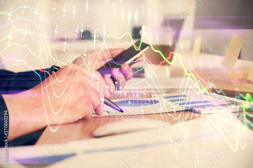 Double exposure of man's hands holding and using a phone and financial graph drawing. Analysis concept.