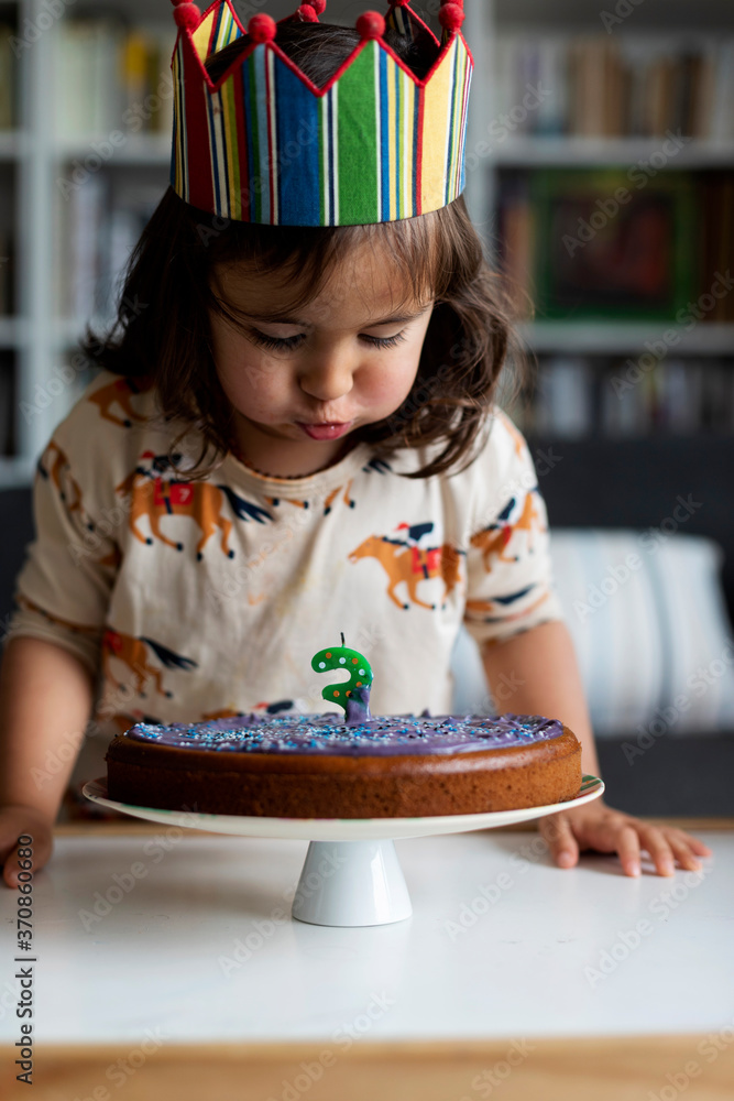 Portrait of little girl blowing out candle on her birthday cake at home Portrait of little girl blowing out candle on her birthday cake at home