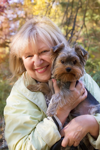 Beautiful smiling woman is holding her pet Yorkshire terrier