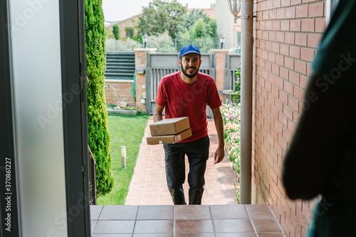 Smiling male postal worker delivering packages to senior woman