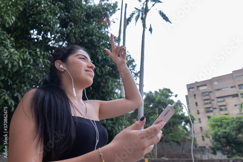 Woman listens to music through a mobile device while moving her arms .