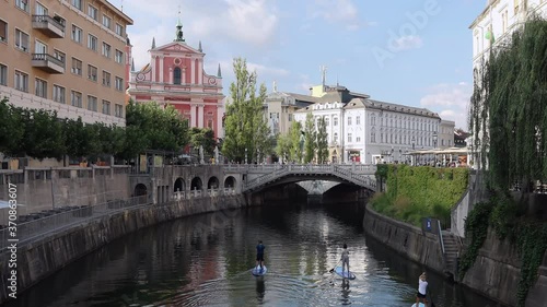 Ljubljana, Slovenia - August 10, 2020: A group of people paddling on boards on the river Ljubljanica towards Tromostovje in the center of Ljubljana, the capital of Slovenia