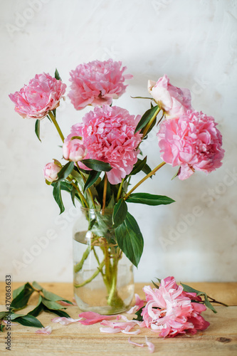 Fototapeta Naklejka Na Ścianę i Meble -  Vertical picture of bouquet of pink peonies in glass jar on on white background. Spring summer floral background with peonies.
