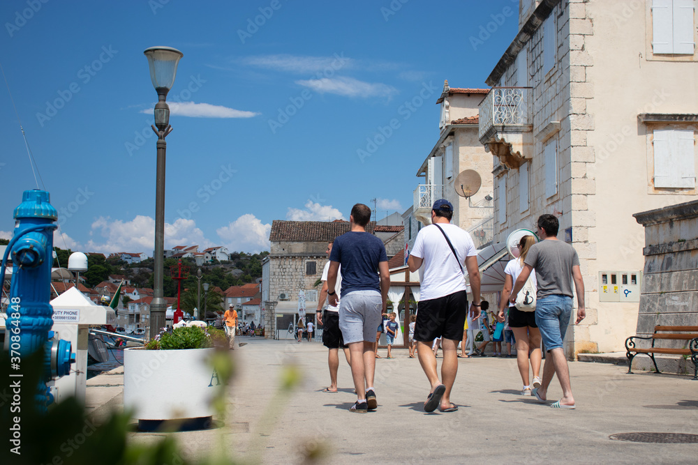 Milna Croatia August 2020 A group of tourists walking along the promenade of a costal town of milna on the island of brac