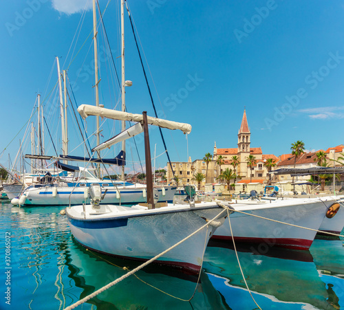 Beautiful panoramic picturesque view of a small town of Milna on the island of Brac. Old boats docked in the crystal clear sea, warm summer day. Old church belltower rising above the buildings photo