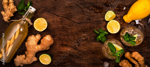 Golden Ginger Ale Beer Cocktail with Lime, Lemon and Mint in glaass on wooden table, top view with copy space