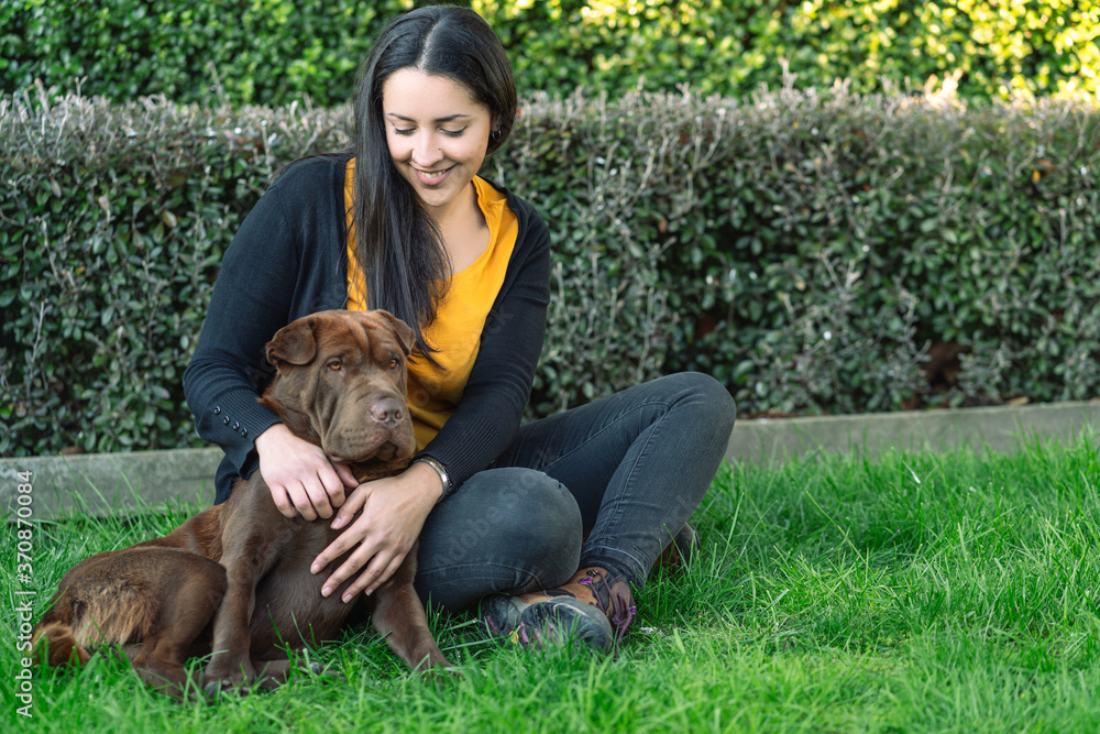 Young woman sitting on the grass next to her dog