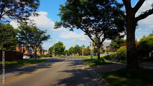 Woman Walks Up To Traffic Light Intersection and Waits to Cross The Street.  Pedestrian Person Walks Along Sidewalk To City Suburb Street Waiting As Busy Traffic Moves Passing By.