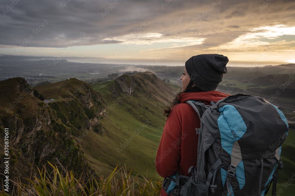 Woman with backpack looking at the horizon at the top of a mountain