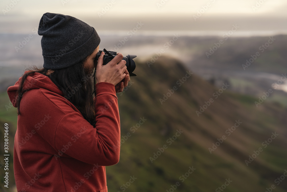 Brunette woman taking a photo with a camera at a mountain landscape Brunette woman taking a photo with a camera at a mountain landscape