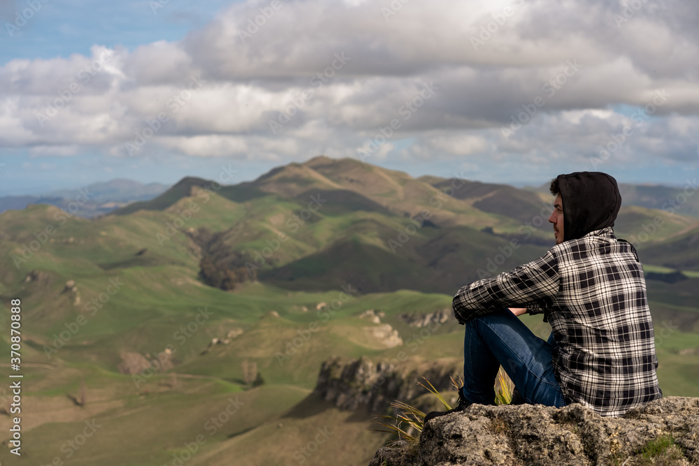 Young man sitting at the top of the mountain in Te Mata Park, Hawke's Bay, New Zealand