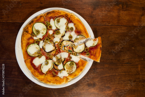 Italian pizza with zucchini, eggplant and green olives seen from above