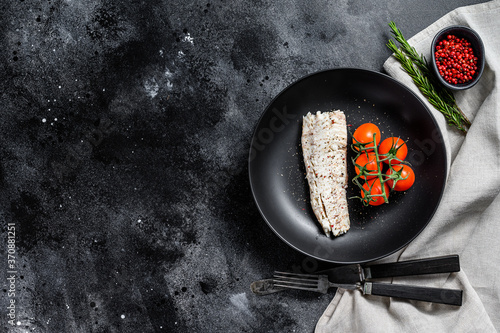 Cooked haddock fillet with cherry tomatoes. Black background. Top view. Copy space