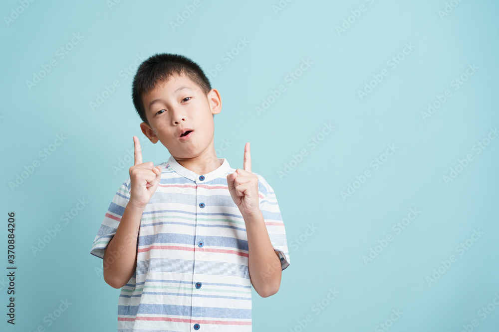 Asian little boy standing thinking on blue background isolated Asian little boy standing thinking on blue background isolated