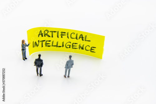 Obraz na płótnie Presentation meeting with miniature figurines posed as business people standing in front of post-it note with Artificial Intelligence handwritten message in background, copy space on the right w salonie
