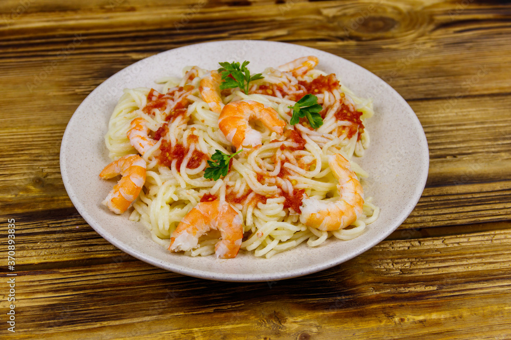 Spaghetti pasta with prawns, tomato sauce and parsley on wooden table Spaghetti pasta with prawns, tomato sauce and parsley on wooden table