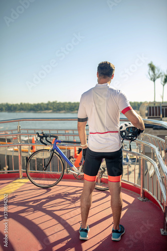 Man in sports cycling clothes standing with his back