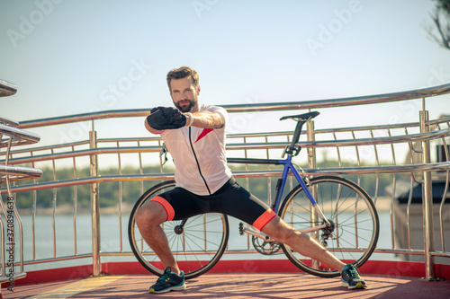 Male athlete doing warm-up near the bike