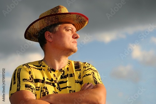 Brutal man in a cowboy hat against a blue sky with clouds