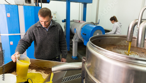 Bilde på lerret Focused man working in handicraft olive oil producing factory, inspecting first