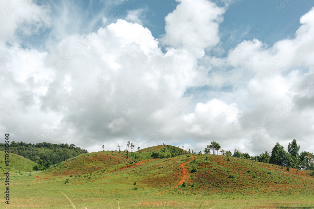 Obraz premium Green small hills with cloudy sky countryside scenery in Thailand.