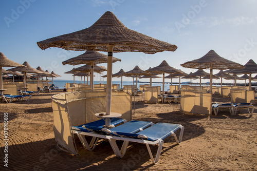 sandy beach with sun loungers thatched umbrellas © dyachenkopro