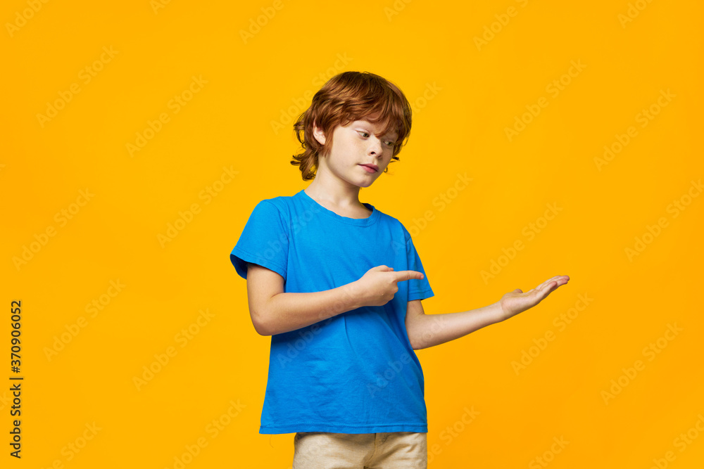 redheaded boy blue t-shirt yellow background freckles and point your finger in the direction of the free space redheaded boy blue t-shirt yellow background freckles and point your finger in the direction of the free space