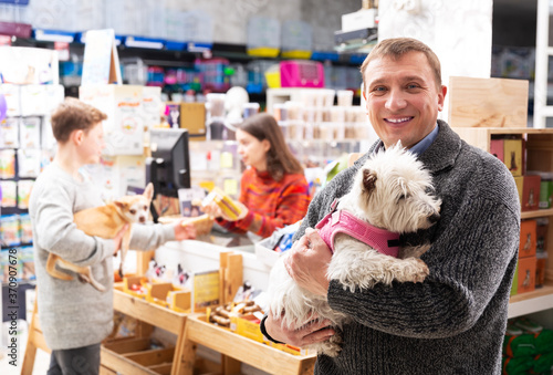 Positive male visitor with west highland terrier dog in petstore photo