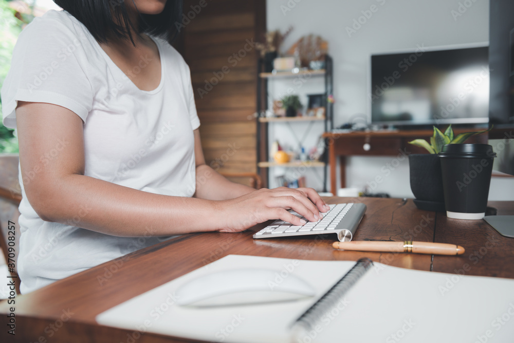 Woman using computer and notebook on workspace with coffee cup in living room,work at home concepts Woman using computer and notebook on workspace with coffee cup in living room,work at home concepts