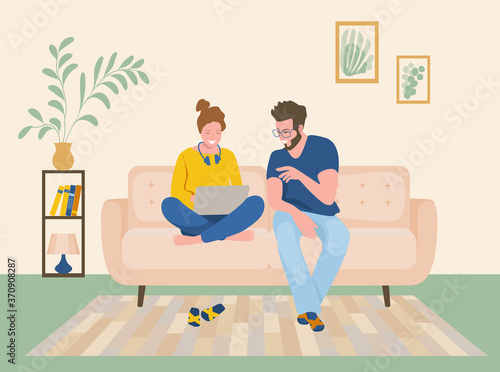 A man and a woman are sitting on the sofa and looking at the laptop screen. Freelance or studying concept. Young family