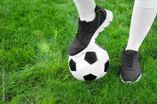 Football player with soccer ball on green grass outdoors © Pixel-Shot