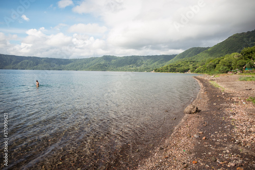 Obraz na płótnie shore of Laguna de Apoyo lake in inactive volcano caldera surrounded by jungle and tourist in the water w salonie
